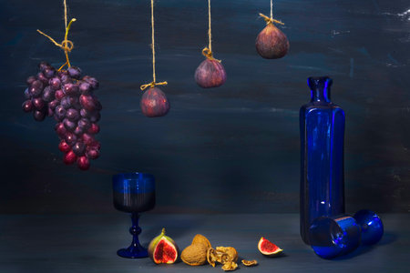 vintage style food still life with figs,walnuts, grapes, and old blue glass bottle