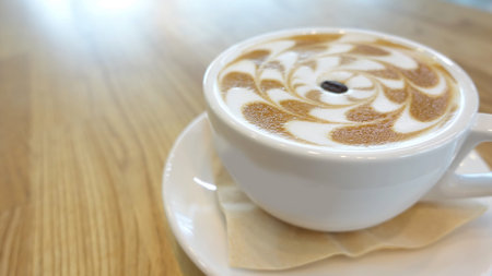 Hot cappuccino coffee in coffee shop on wooden table