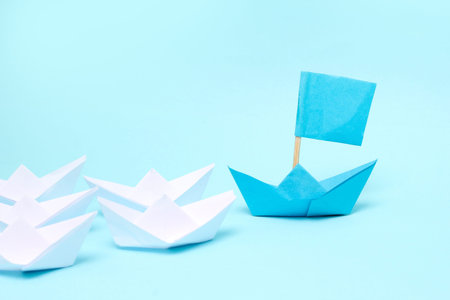 Leadership concept, blue paper ship leading among white on white background