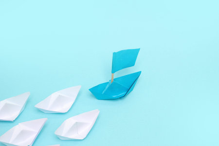Leadership concept, blue paper ship leading among white on white background