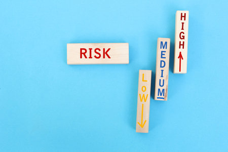 The words risk, medium, high and low written on wooden blocks with a stickman walking towrads the risk zone. Risk assesment, analysis or risk taking conceptの写真素材