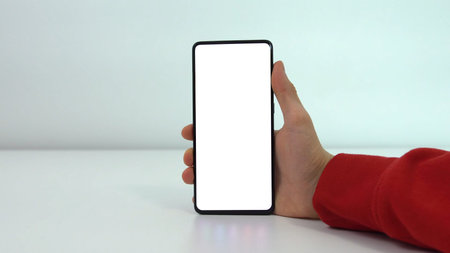 Mockup image of hand holding mobile phone with blank white screen . Man uses his Mobile Phone