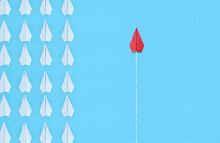 Group of white paper plane in one direction and one red paper plane pointing in different way on...