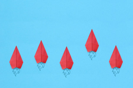 Red paper plane leading among a Red planes on blue background. Business competition and Leadership...
