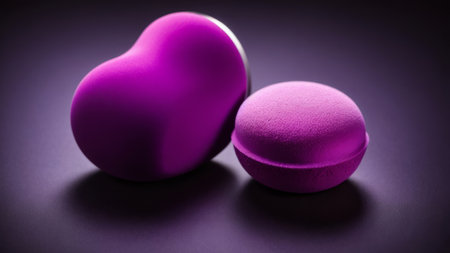 Two pink heart-shaped dumbbells on a dark background.の素材