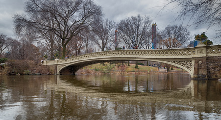 The bow bridge in central park, New York city daylight view with reflection in water and clouds,trees and Manhattan buildings in backgroundのeditorial素材