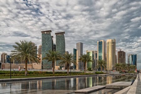 Doha, Qatar-November 18,2019: Doha, Qatar  Skyline daylight view from Sheraton park with reflection in the water and clouds in sky in backgroundのeditorial素材