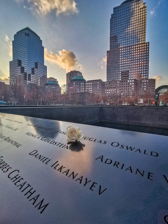 New York , USA-December 14,2019:  9/11 memorial with white flower in foreground and skyscrapers in...
