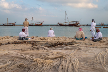 Doha,Qatar-December 11,2019: Traditional Arabic fishermen sitting and standing  on Katara beach with...