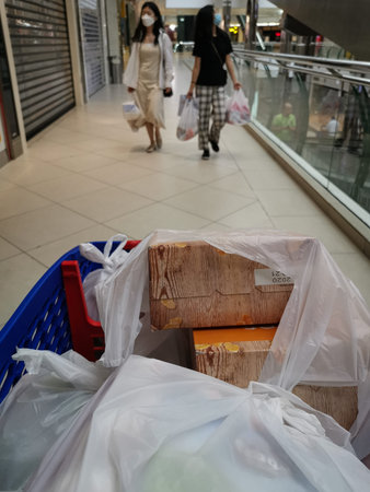 Doha,Qatar-March 23,2020: Corona virus safe shopping, the photo shows a shopping cart in the foreground and two walking women wearing medical masks and carrying shopping bags in the backgroundのeditorial素材