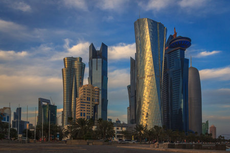 Doha Qatar skyline in daylight showing modern skyscrapers , cars, trees, clouds and street.