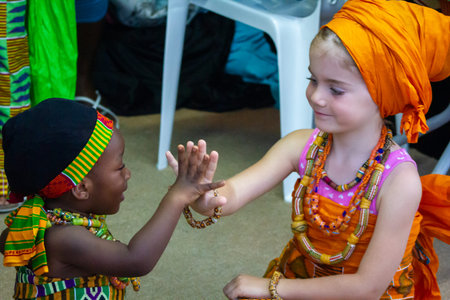 African and white (Caucasian) girls sitting together looking to each others and touching handsのeditorial素材