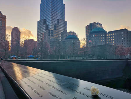 9/11 memorial in New York , USA with white flower in foreground and skyscrapers in backgroundのeditorial素材