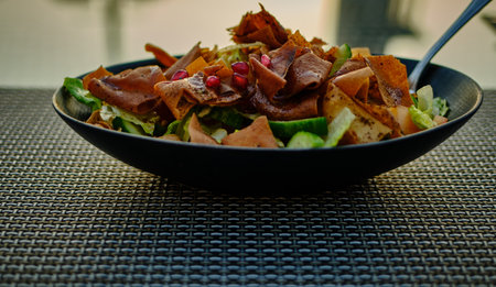Fattoush (Lebanese salad) close up  image in a black plate . It is made with vegetables and crispy toasted flatbread, which soaks up the dressing beautifully.の写真素材