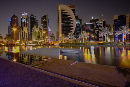 Doha skyline in west bay area night shot taken from the Sheraton park with artificial lake in foreground  and reflection from skyscrapersのeditorial素材