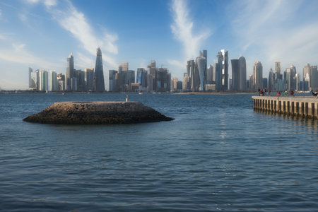 Doha skyline from the corniche promenade afternoon shot showing dhows with Qatar flag in the Arabic gulf  in foreground and clouds in the sky in backgroundのeditorial素材