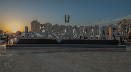 Porto Arabia in The pearl Doha, Qatar sunset shot showing Love QATAR sign in foreground with Yachts ,boats and residential buildings in backgroundの写真素材