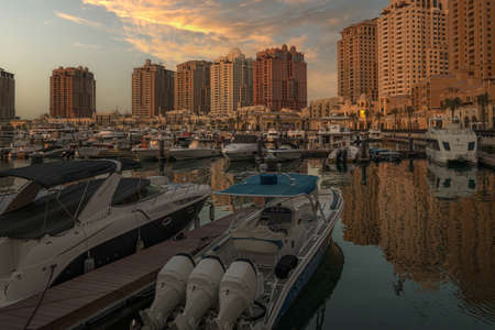 Porto Arabia Marina in The pearl Doha, Qatar sunset  shot showing luxurious yachts docked at the marina with  residential buildings in background.のeditorial素材