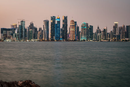 Doha Qatar skyline at night showing skyscrapers lights reflected in the Arabic gulf