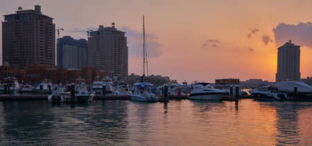 The pearl Marina in Porto Arabia , Doha Qatar sunset view with Yachts in foreground, buildings and clouds in the sky in backgroundのeditorial素材