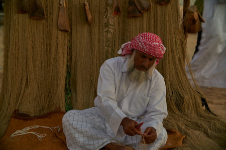 A traditional Arabic craftsman weaving fishnet in Katara cultural village, Doha Qatar daylight view...