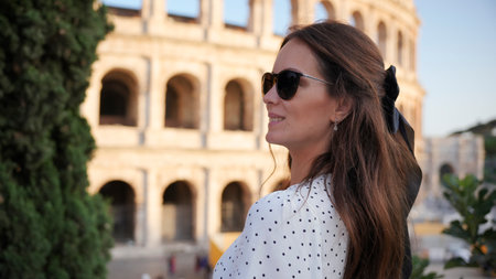 Stylish woman in polka-dot dress admiring the Colosseum in Rome, Italyの写真素材