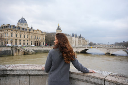 Woman Admiring Seine River and Paris Architecture on a Cloudy Dayの写真素材