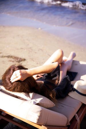 Woman relaxing on beach lounge by the shoreの写真素材