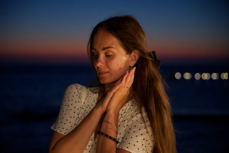 Serene woman at sunset with ocean backdropの写真素材