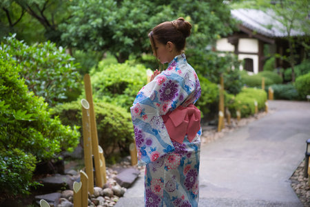 Woman in Floral Kimono Reflecting in Tranquil Japanese Gardenの写真素材