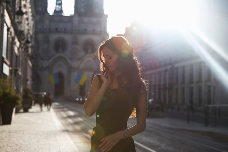 Woman in black dress walking in sun flareの写真素材