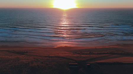 Drone Captures Ocean Sunset Over Sandy Beach and Wavesの写真素材