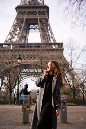 Curlyhaired woman walking near Eiffel Tower on a clear day