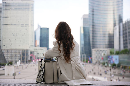 Woman sitting and observing La Defense district skyline in Parisの写真素材