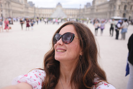 Woman taking selfie at Louvre courtyard in Parisの写真素材