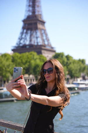 Woman taking selfie with Eiffel Tower in Parisの写真素材