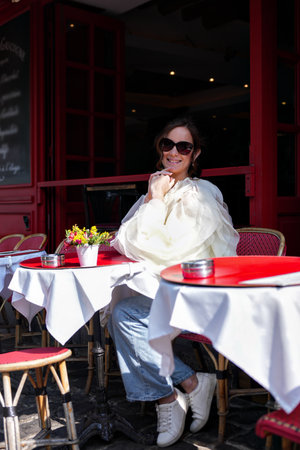 Woman sitting at Paris street cafe on sunny dayの写真素材