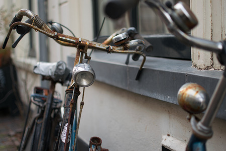 Two vintage and rusty bicycles against the wall looking each other, in Harlem, Netherlands, 2015のeditorial素材