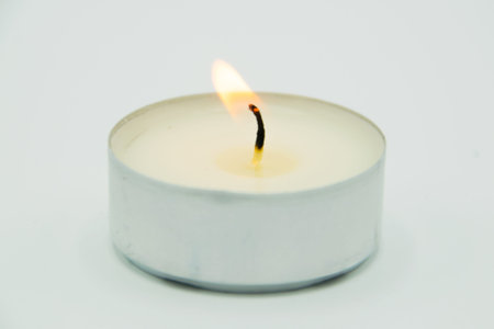 burning wax candle on gray background