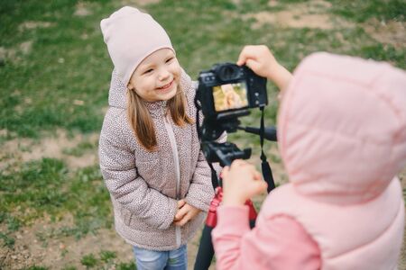 Children with photo camera in a city park. Two girls make a video and photo for the Internet, record a video blog for camera.の写真素材