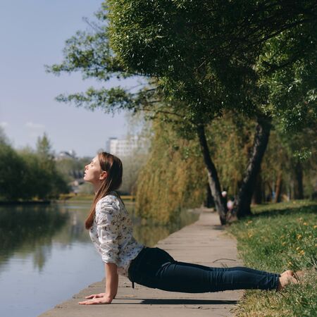girl in cobra pose on a park background. healthy lifestyle concept. yoga outsideの写真素材