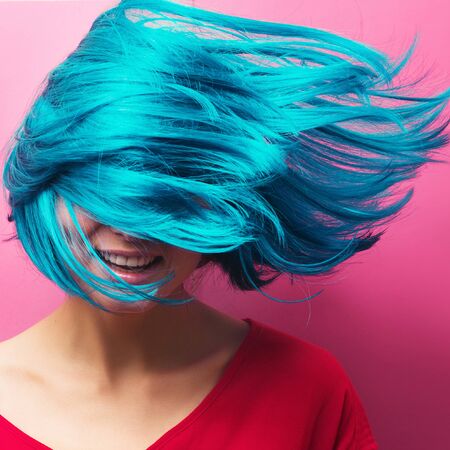studio portrait of a sexy beautiful girl with a smile in motion on a pink background. Girl with blue hairの写真素材