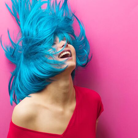 studio portrait of a sexy beautiful girl with a smile in motion on a pink background. Girl with blue hairの写真素材