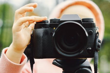 girl shoots on a vintage film camera close-up on the background of forestの写真素材