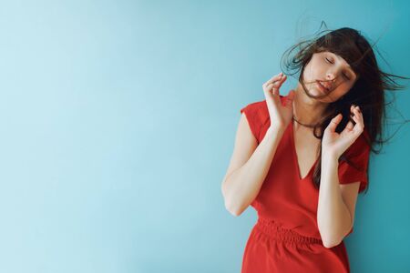 studio portrait of a girl in a red dress. fluttering brunette hairの写真素材