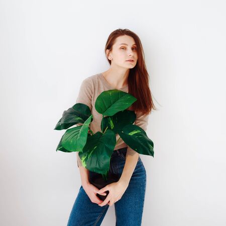 hipster girl in blue jeans with a flower pot in hand on a white backgroundの写真素材