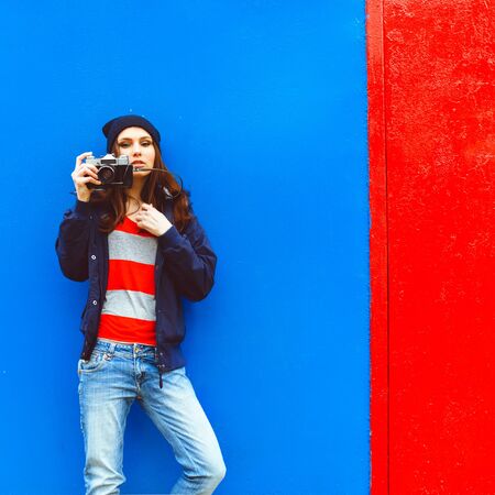 portrait of a beautiful hipster girl with a camera on the background photon makes blue walls and red doorsの写真素材