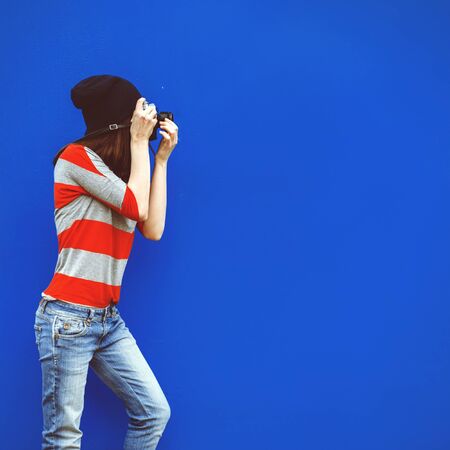 portrait of a beautiful girl with a shutting camera on a red backgroundの写真素材