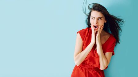 studio portrait of a girl in a red dress with surprise on her facÑの写真素材