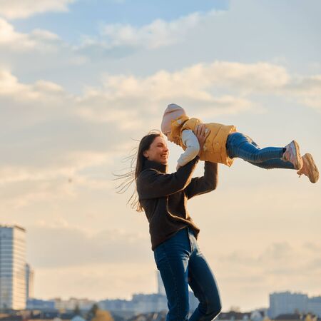 portrait of mom with a daughter in her arms against the backdrop of the cityscapeの写真素材